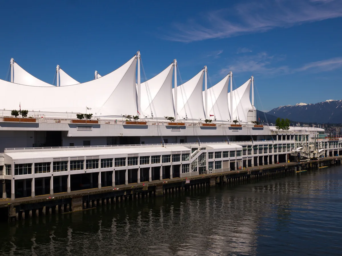 The white sails of Canada Place on the harbour with snowy North Shore mountains behind, on a clear day.