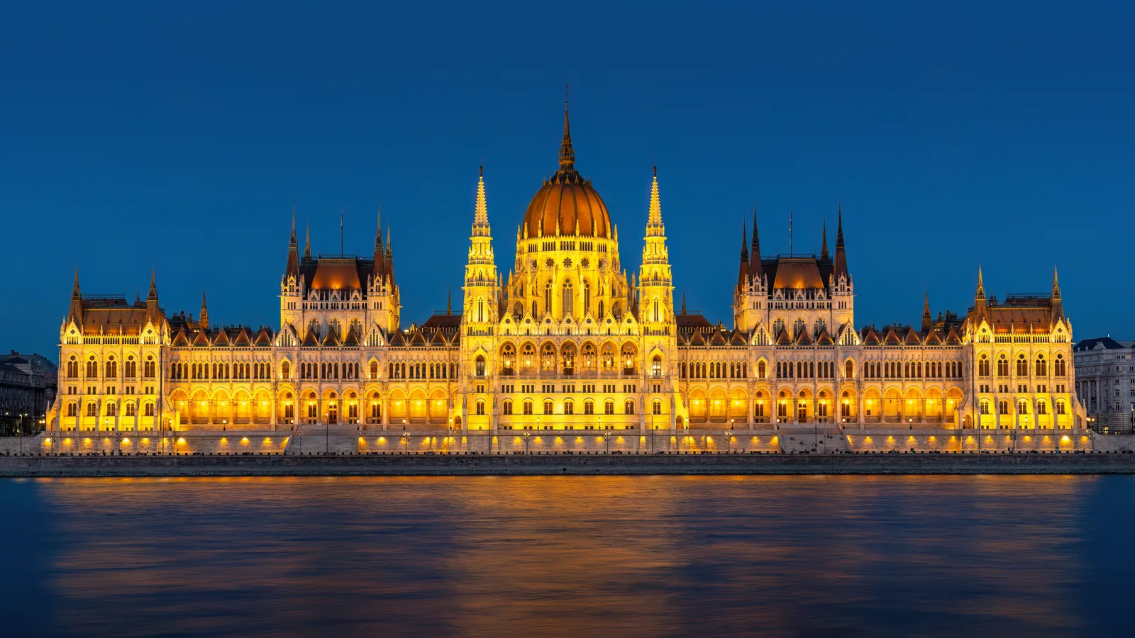 The illuminated Hungarian Parliament Building reflected in the Danube at blue hour.