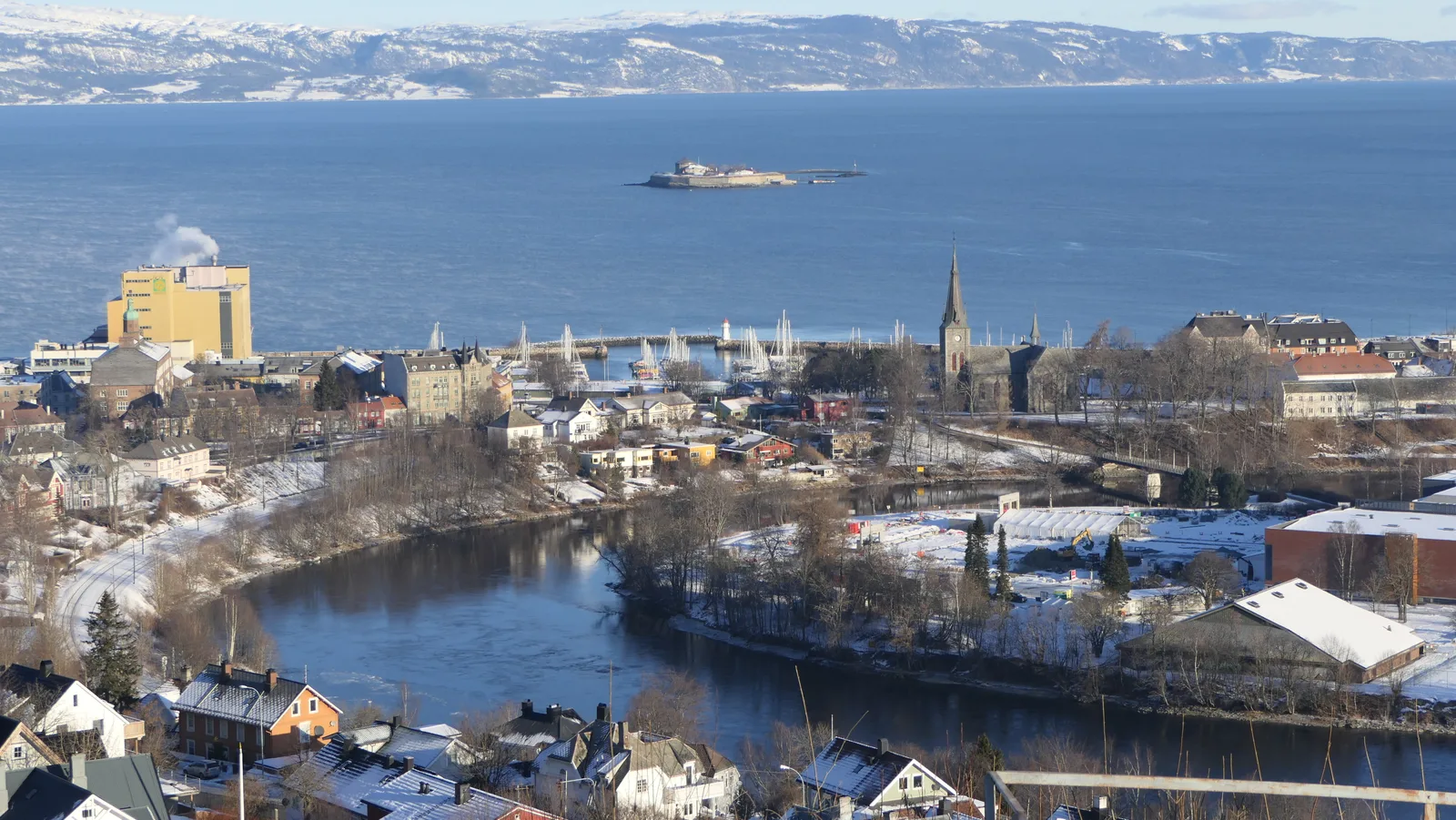 Trondheimsfjord, the island of Munkholmen and the Nidelva river bend from a hilltop over Trondheim in winter.