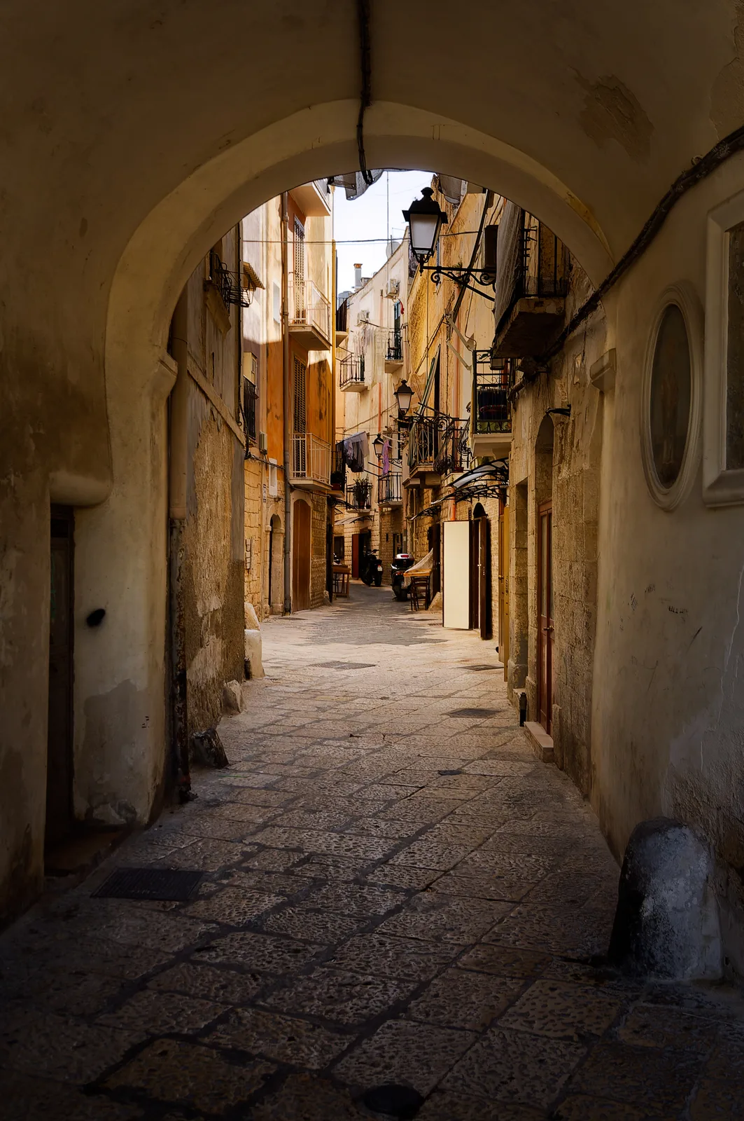 A stone archway opening onto a quiet lane in Bari Vecchia.