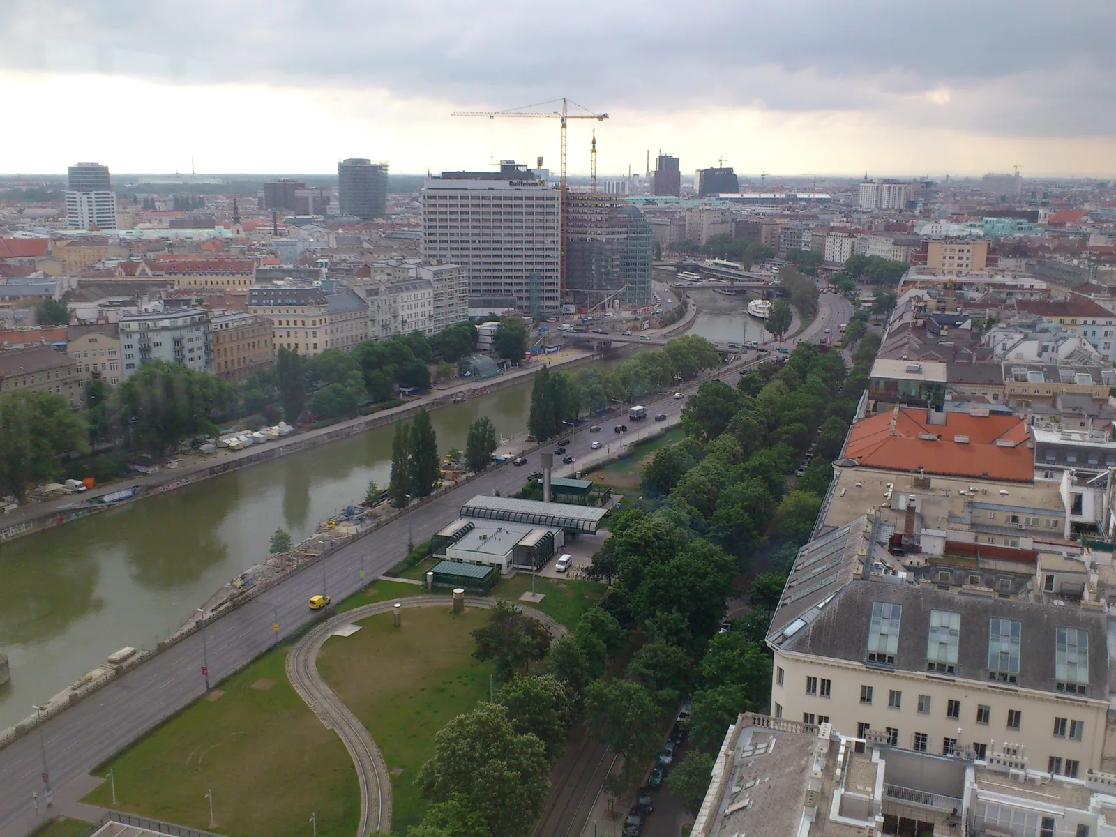 The Donaukanal running between tree-lined banks seen from above, with city blocks on both sides.