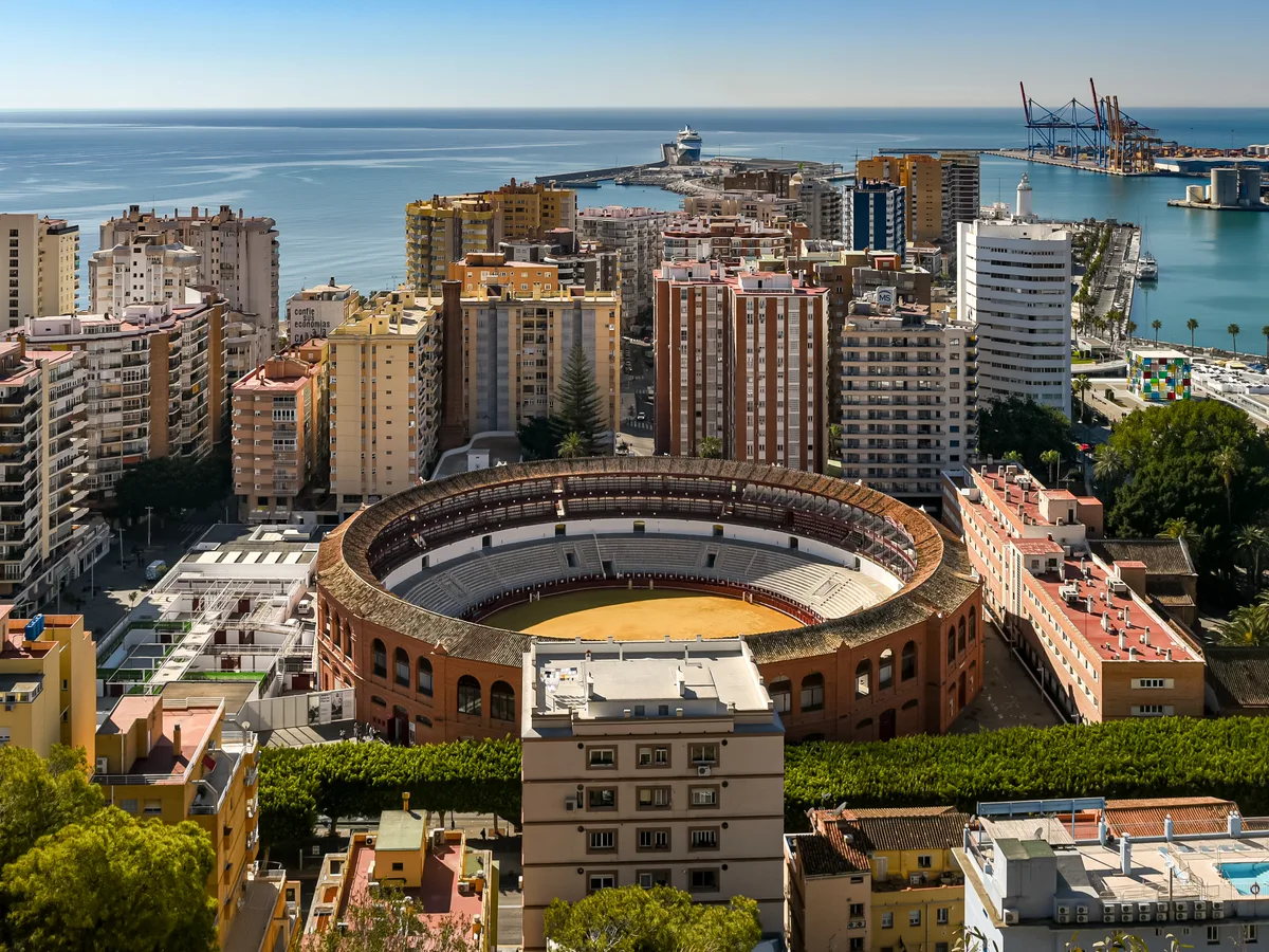 The bullring and the high-rise coast of Málaga with the sea beyond, seen from the hill above.