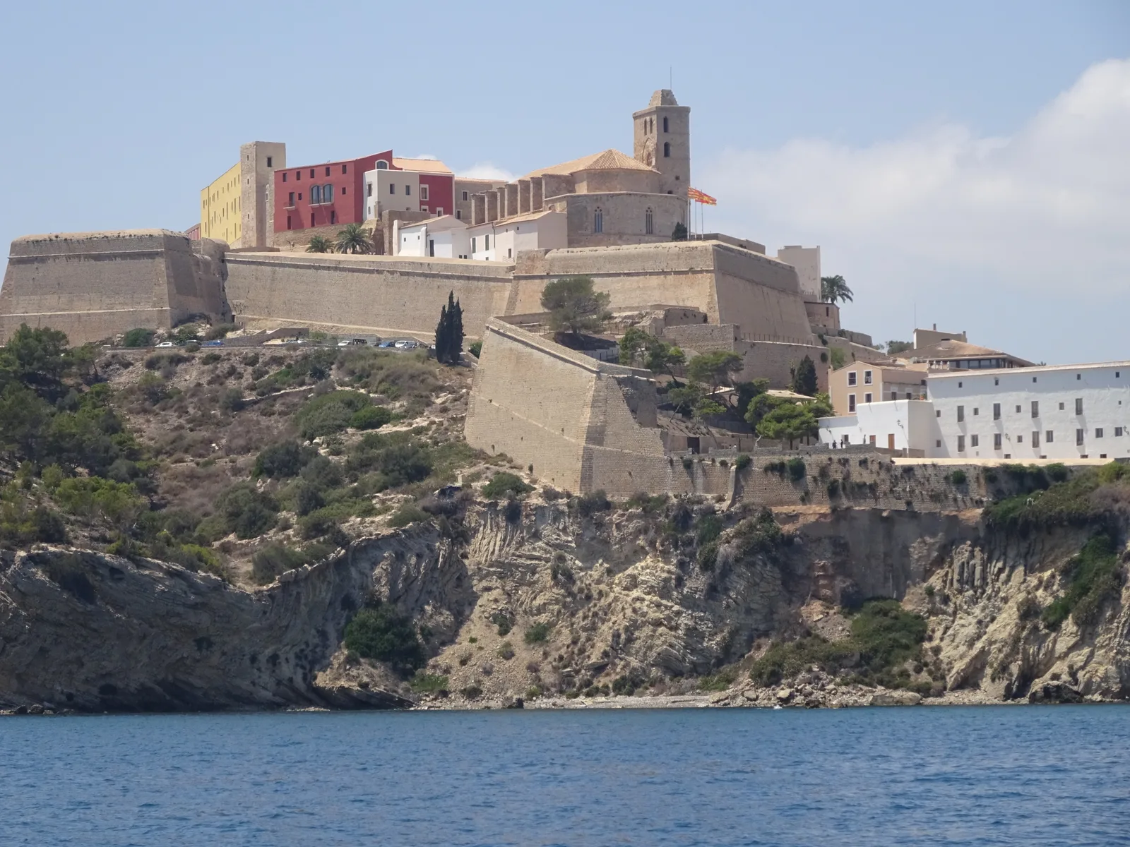 The fortified old town of Ibiza rising above the sea on its cliff, seen from the water.