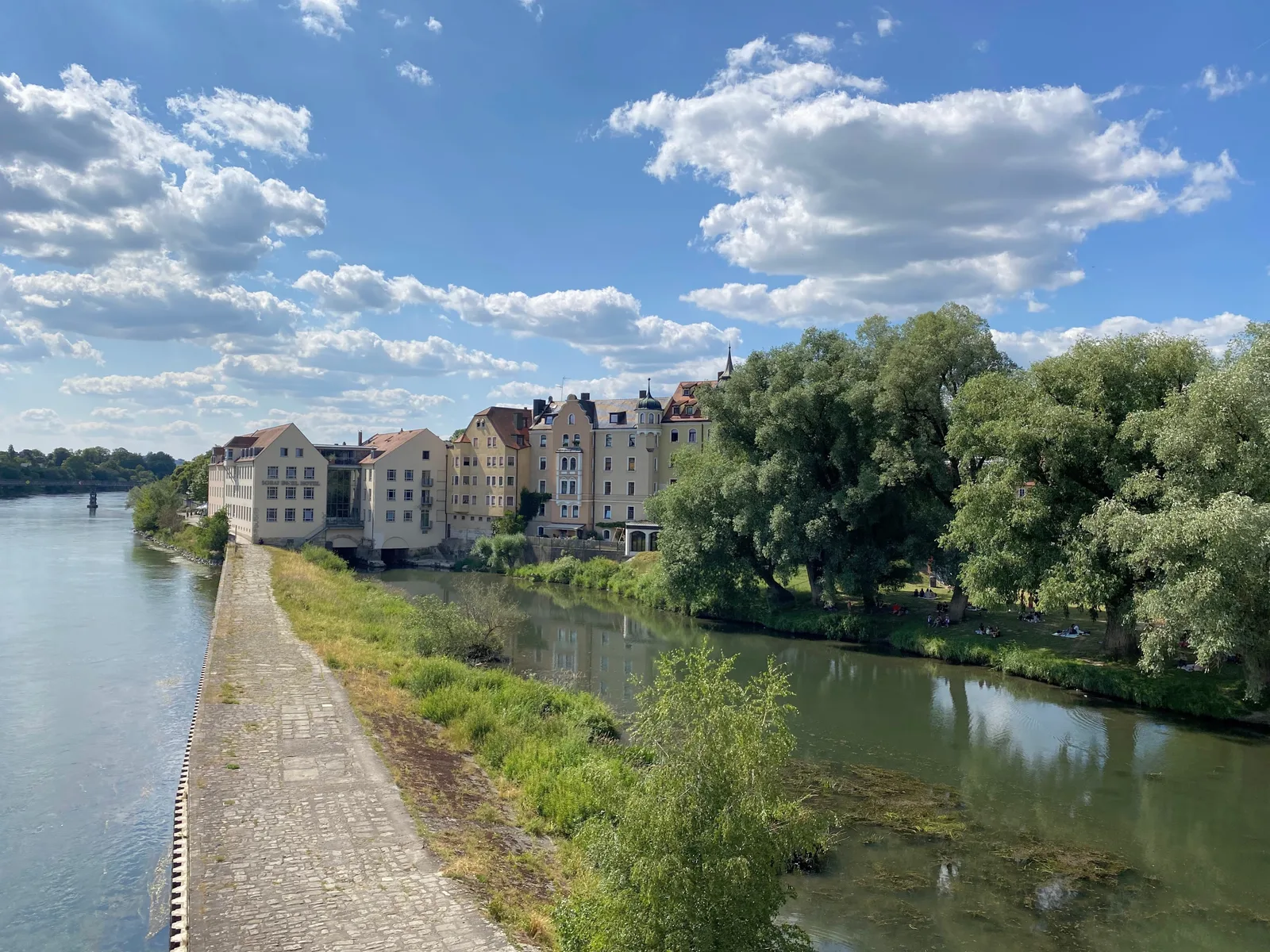 A grassy spit and old houses on the Danube bank of Regensburg seen from the Stone Bridge.