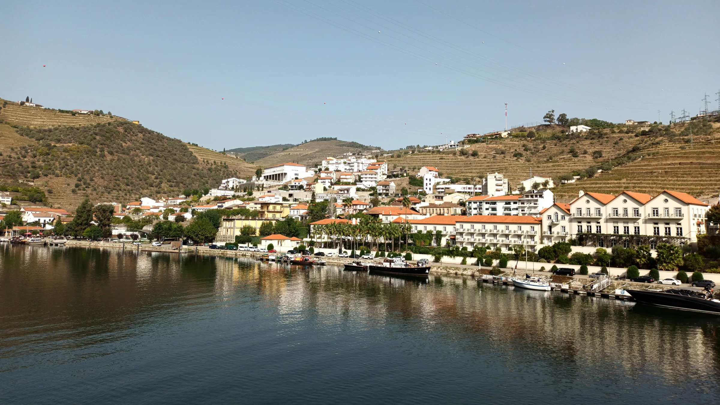 The village of Pinhão on the Douro, with the hotel and river-front reflected in calm water below terraced slopes.