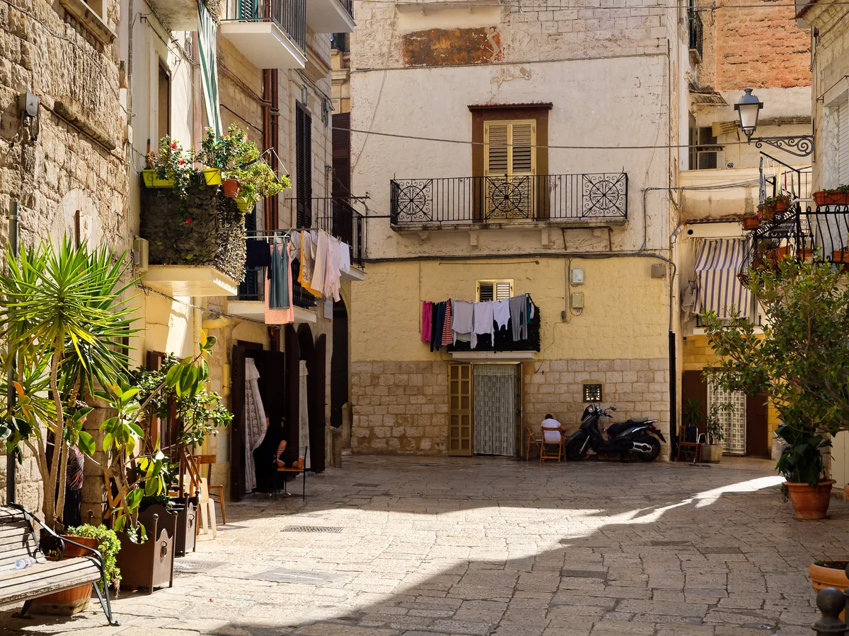 A quiet sunlit corner of Bari Vecchia with limestone houses, plants and washing lines.