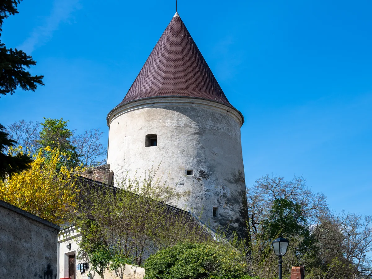 The white Pulverturm tower with a conical roof at the end of a cobbled lane in Krems.