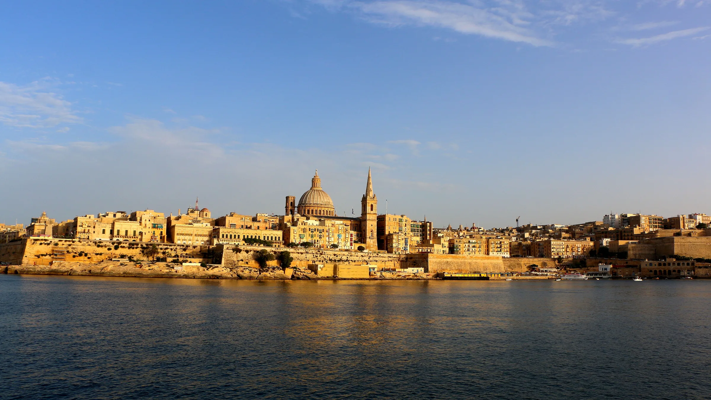 Valletta ramparts and domes glowing in warm light across the Grand Harbour.
