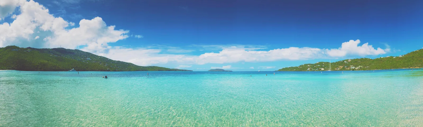 A wide panorama of the turquoise water and green headlands of Magens Bay on St. Thomas.