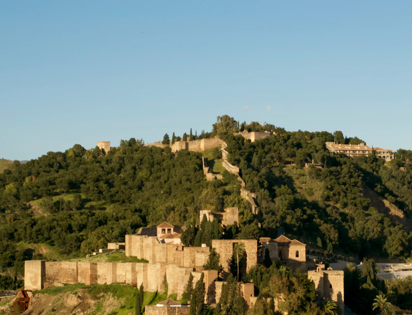 The Gibralfaro hill and castle walls above Málaga on a clear evening.