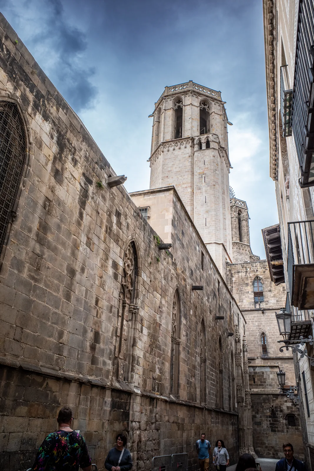 A narrow street in Barcelona's Gothic Quarter lined with tall stone buildings and wrought-iron balconies