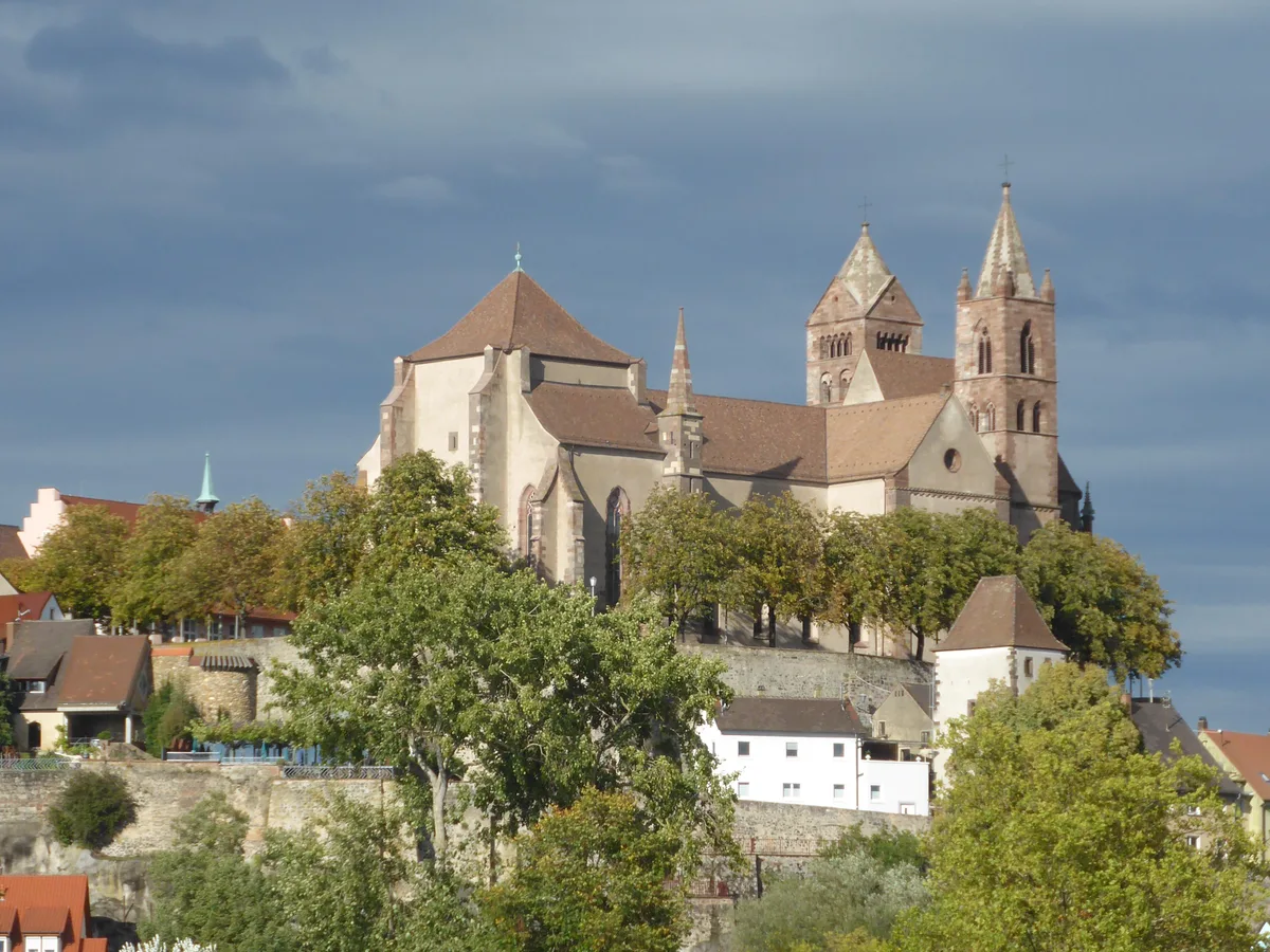 Breisach Minster on its hill above the Rhine town with dark storm clouds behind.