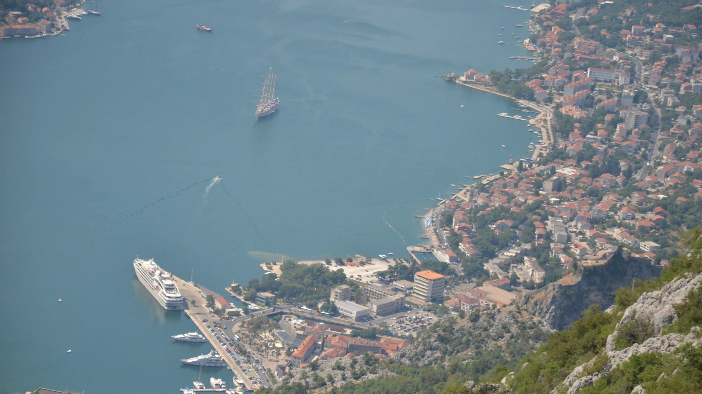 Kotor old town and port seen from the fortress path with a cruise ship alongside and the bay stretching away.