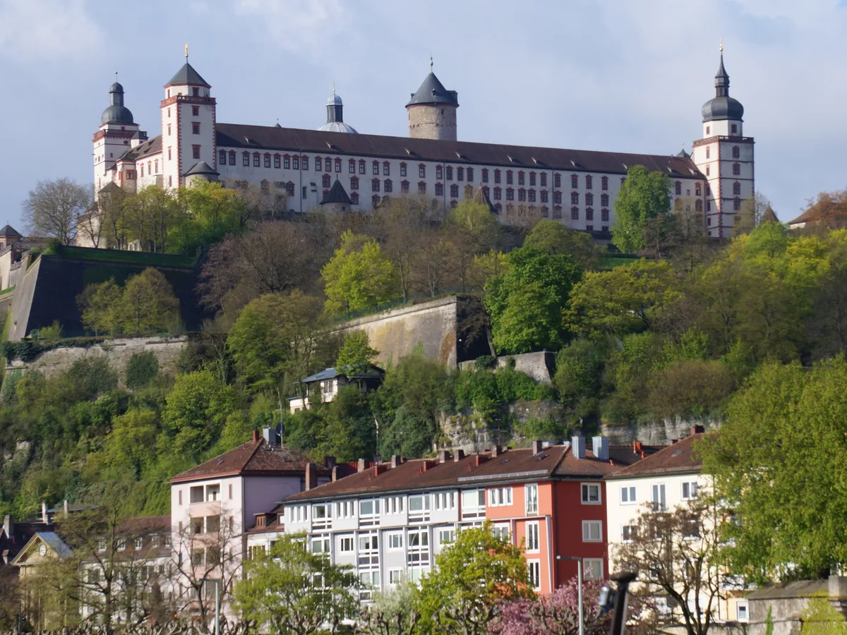 The Marienberg Fortress above the Main river and a green riverbank in Würzburg.