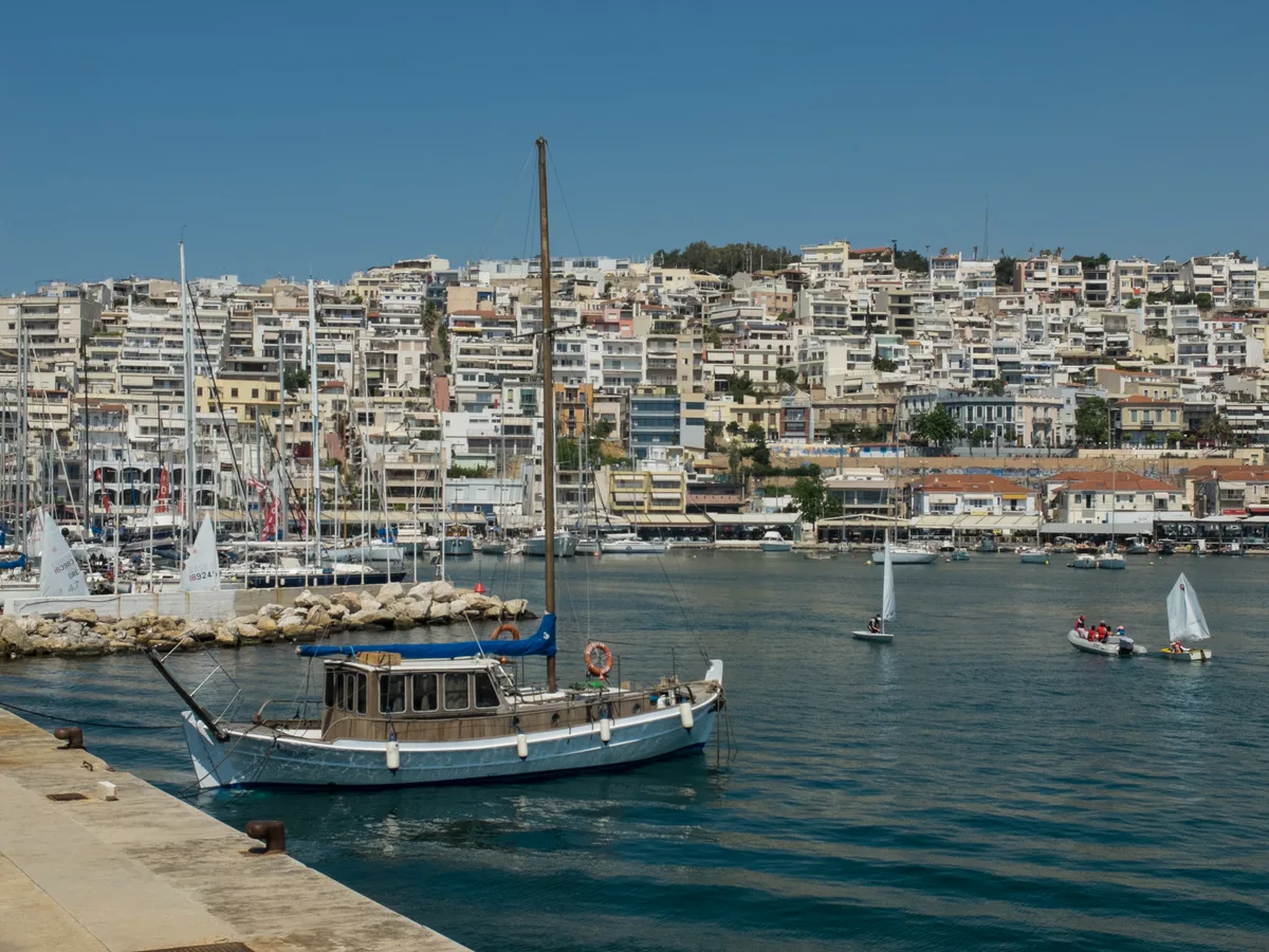 Fishing boats and small sailing yachts in Mikrolimano harbour, Piraeus, with a traditional wooden caique in the foreground.