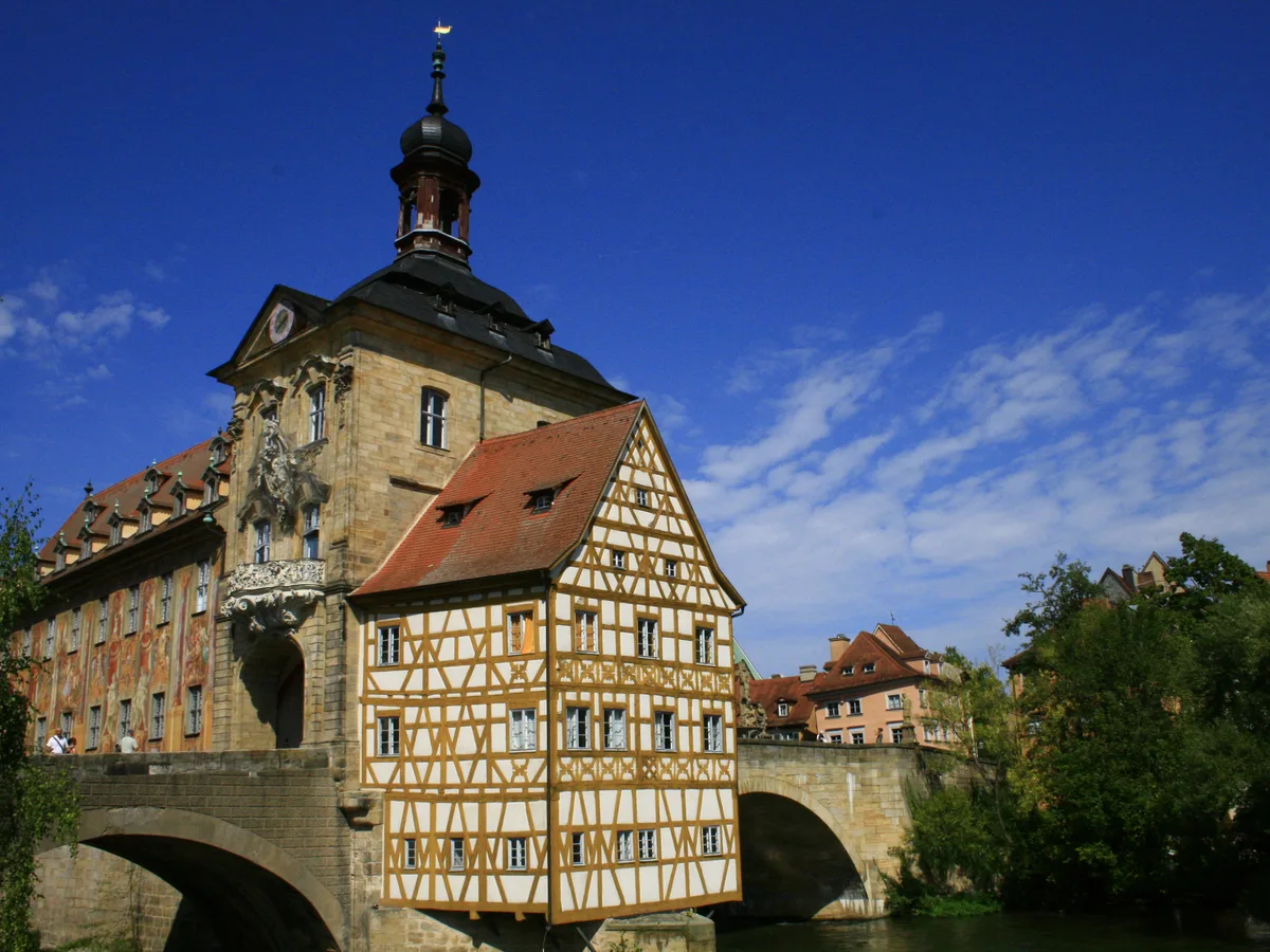 The Old Town Hall of Bamberg standing on a small island in the Regnitz with a stone bridge arching on both sides.