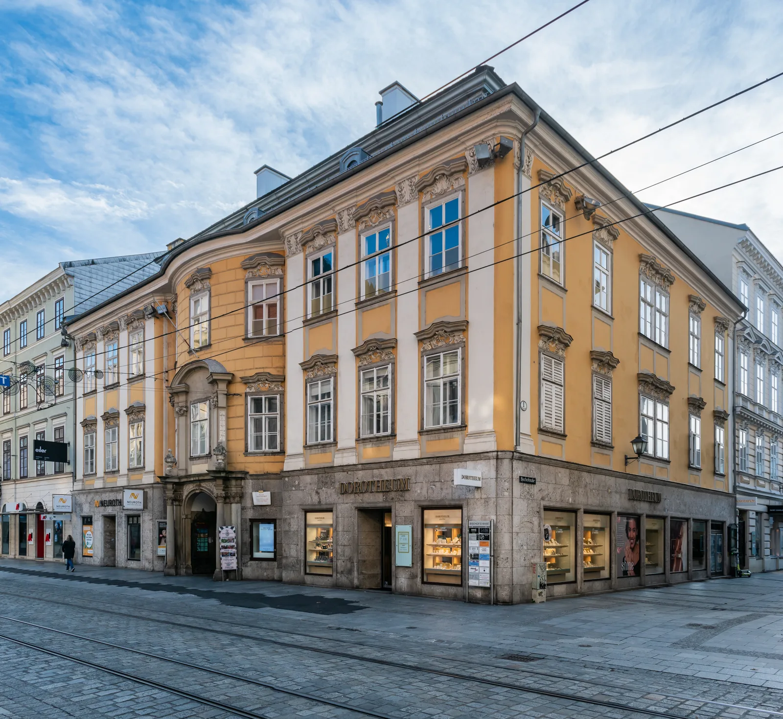 A corner building with an ochre facade and tram tracks in the street in the old town of Linz.