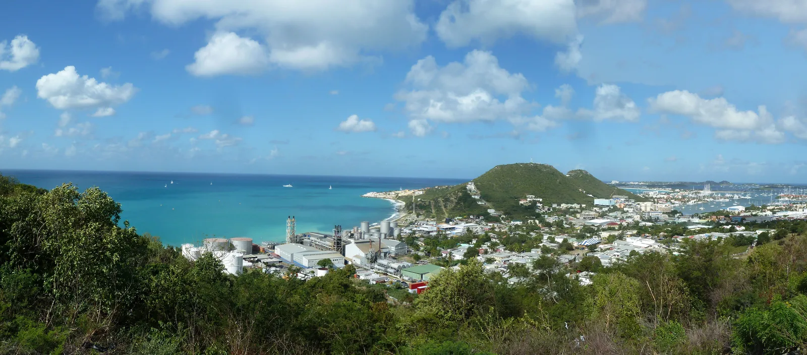 A wide hillside view over Cole Bay and Simpson Bay on Sint Maarten with turquoise sea and the town below.