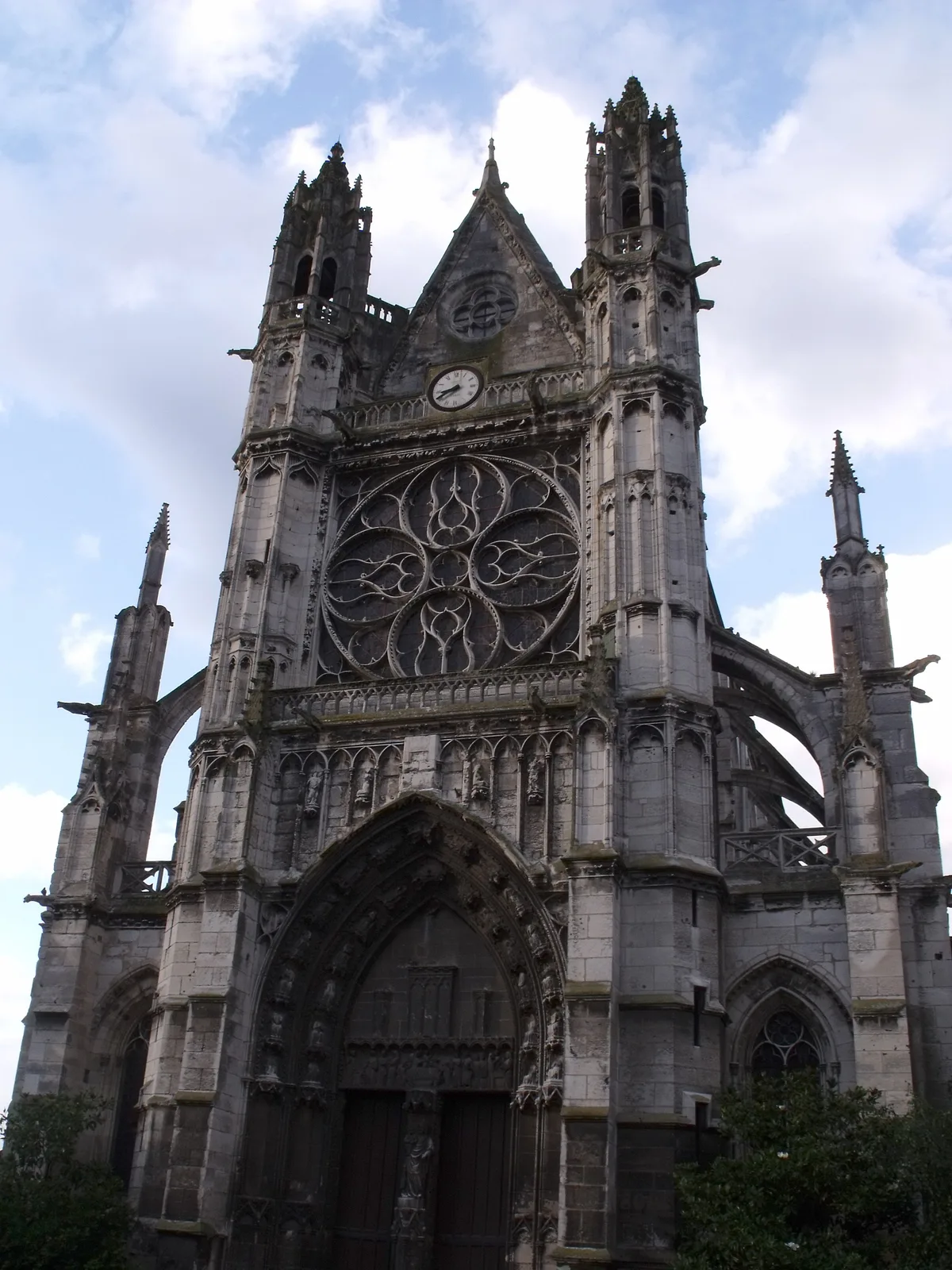 The west front of the Notre-Dame collegiate church in Vernon under a pale sky, with spires and a rose window.