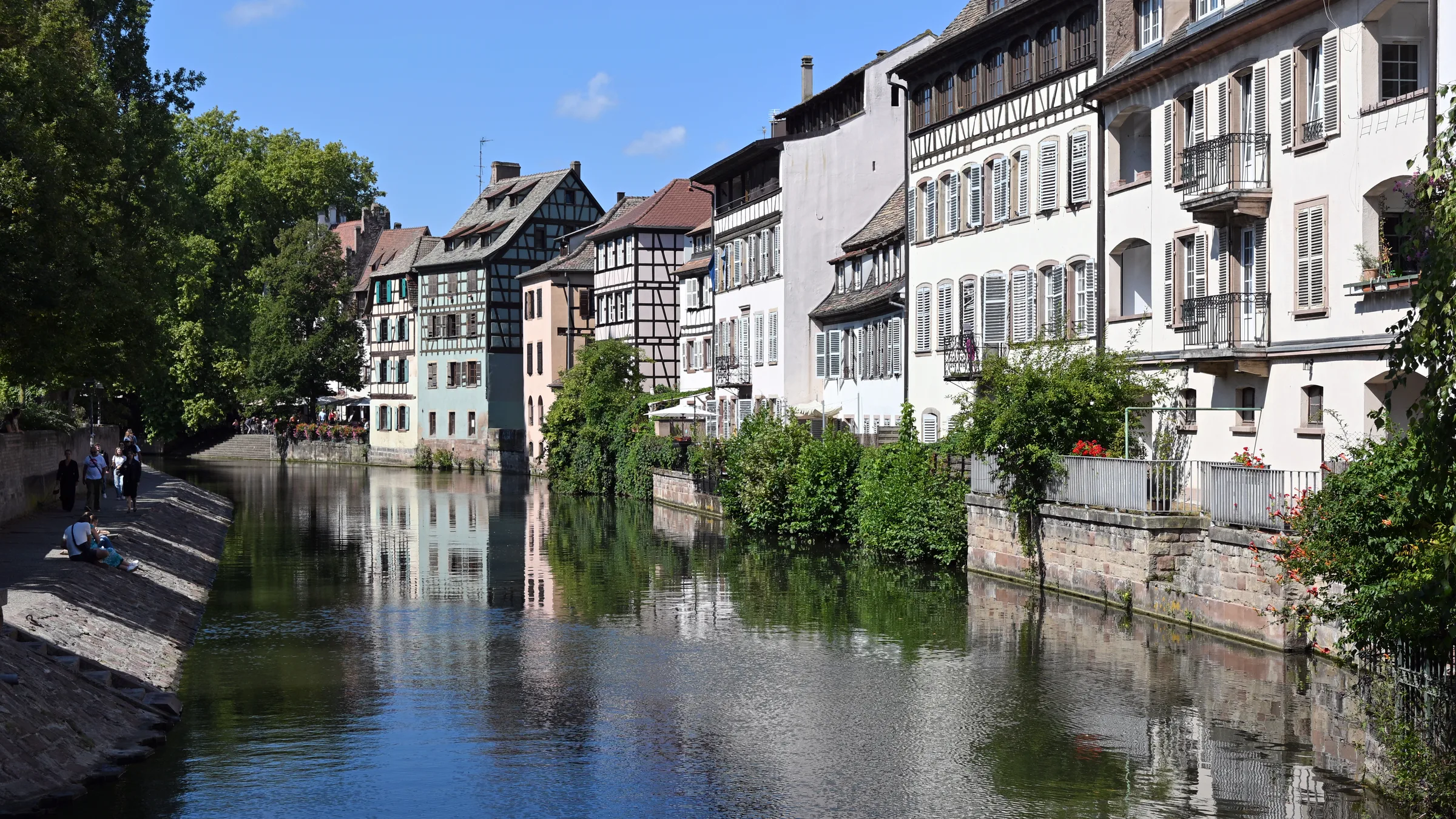 Timber-framed houses on the Ill canal in Petite France, Strasbourg, reflected in the water on a bright day.