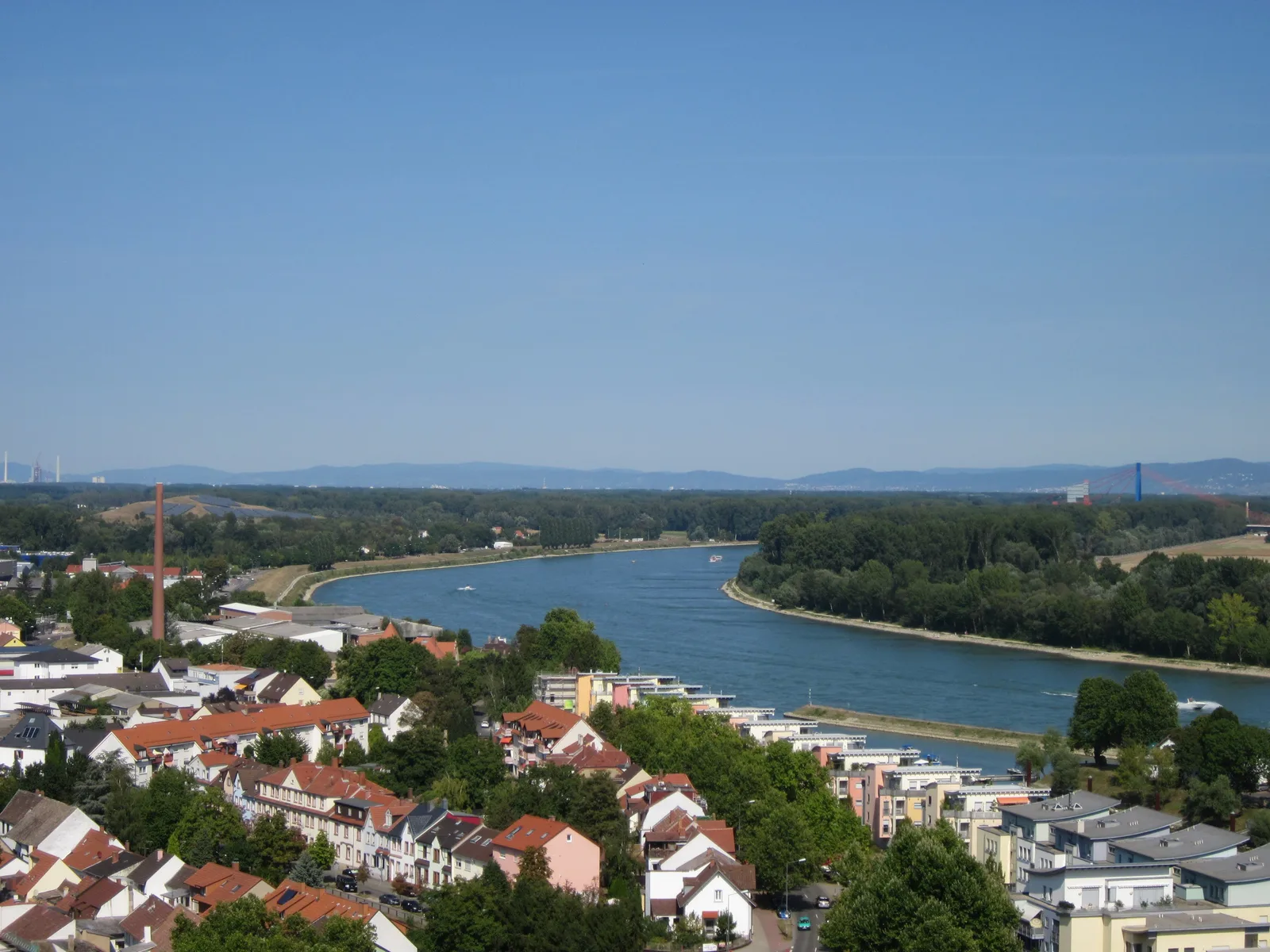 A view from the cathedral tower over Speyer rooftops, a bend in the Rhine and flat floodplain beyond.