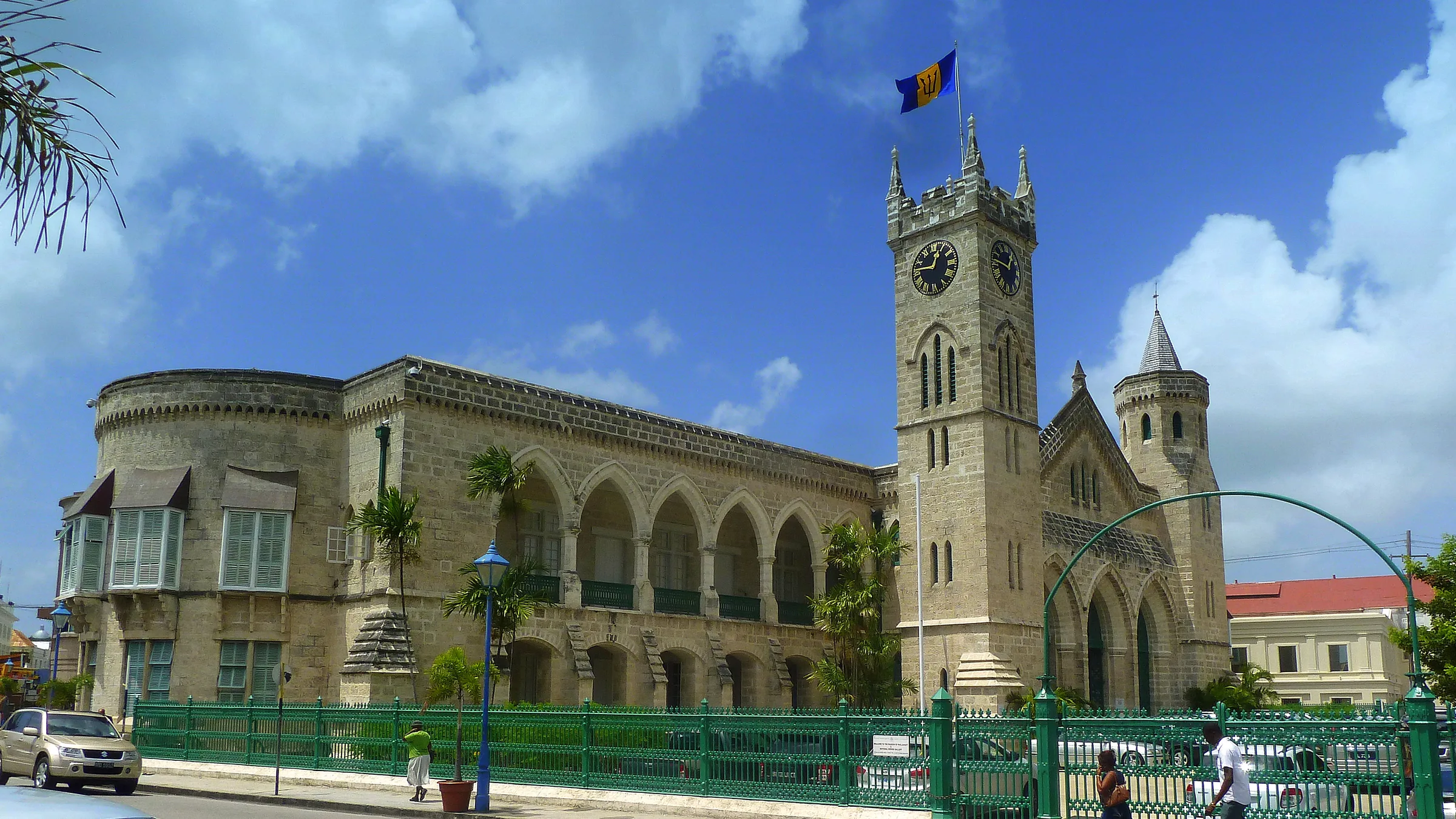 The Parliament Buildings of Barbados with their clock tower and a flag against a blue sky in Bridgetown.