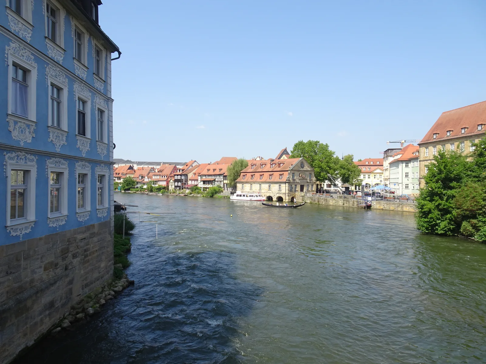 The Regnitz weir and the Schlachthaus building beside the water in Bamberg, with a footbridge in the distance.