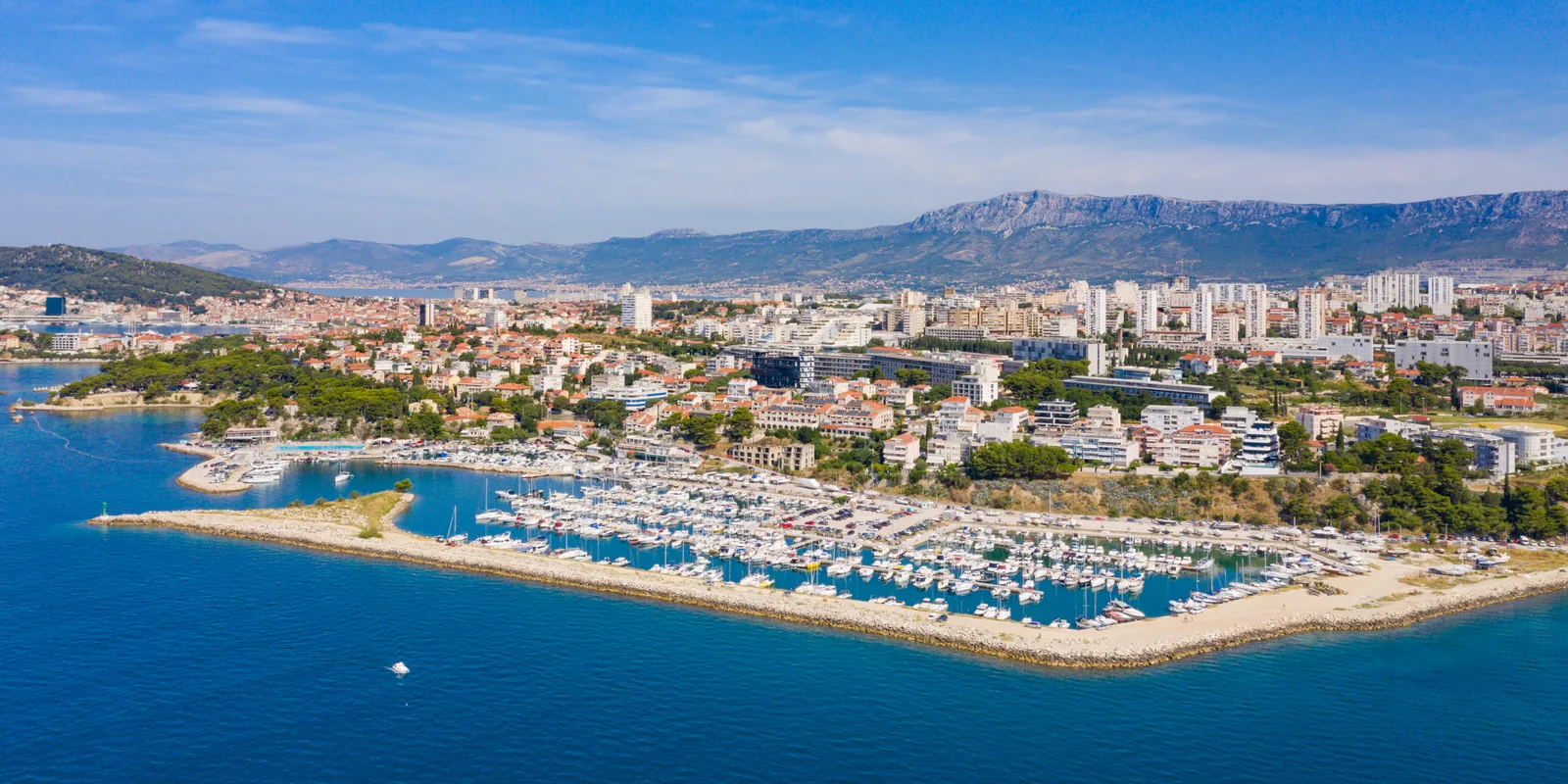 Aerial view of the Zenta marina in Split with hundreds of moored boats and the city and mountains behind.