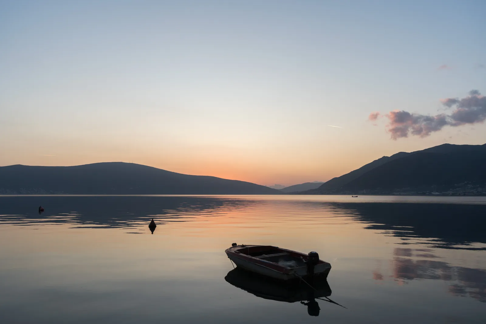 A small rowing boat silhouetted on still water at sunset in the Bay of Kotor.