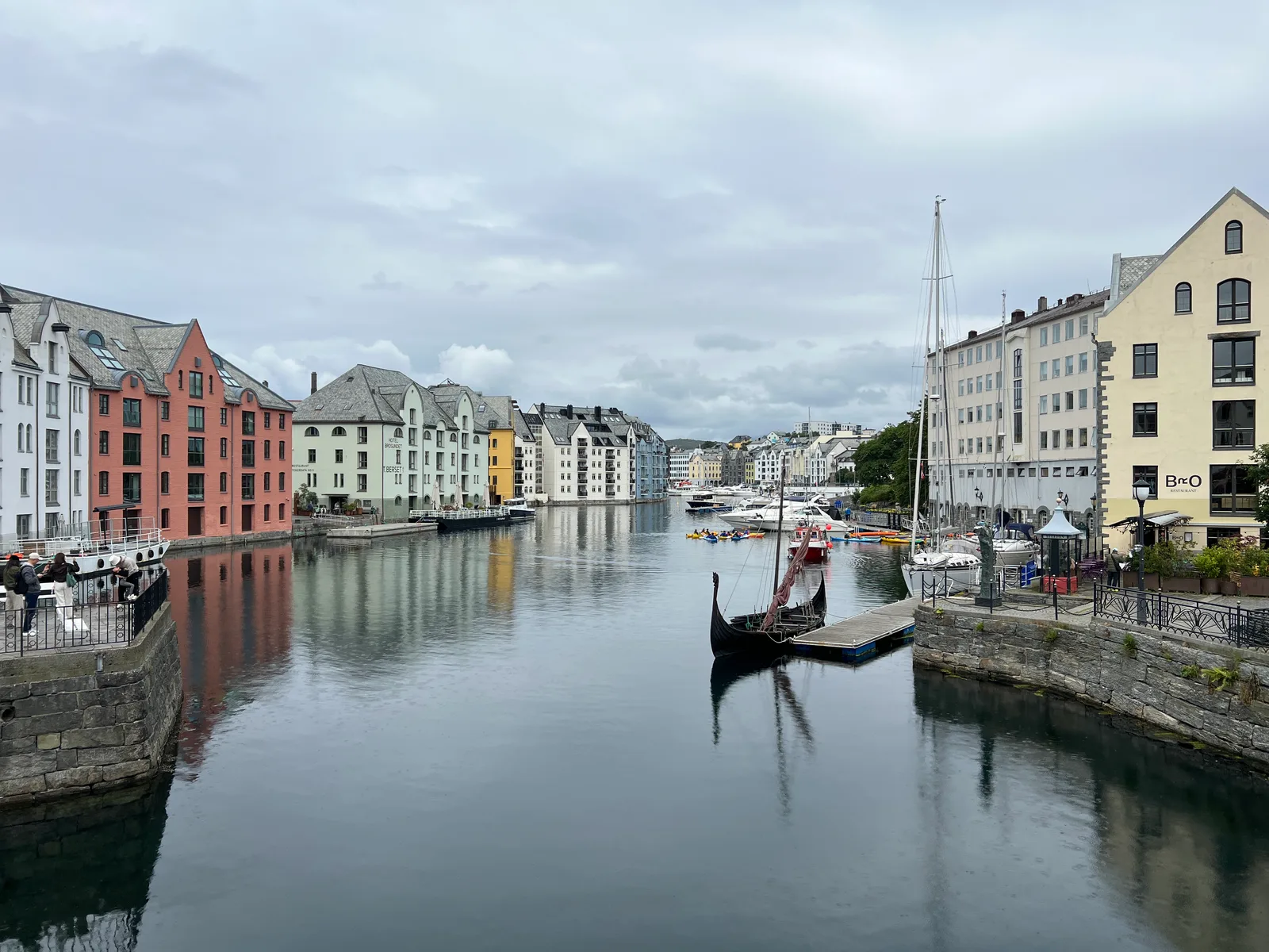 The Hellebrua view along the Alesundet canal with pastel Art Nouveau buildings and a Viking longship replica.