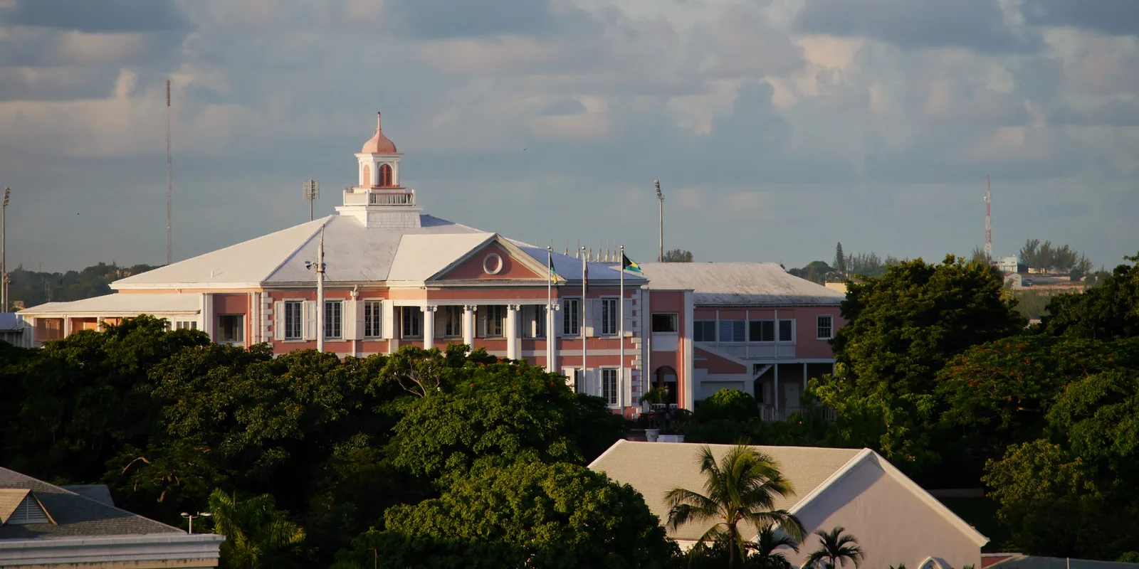 The pink Government House roofline and cupola above trees and rooftops in Nassau.