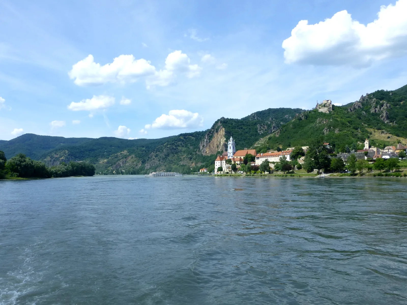 A wide view along the Danube towards Dürnstein under blue sky, seen from the river.