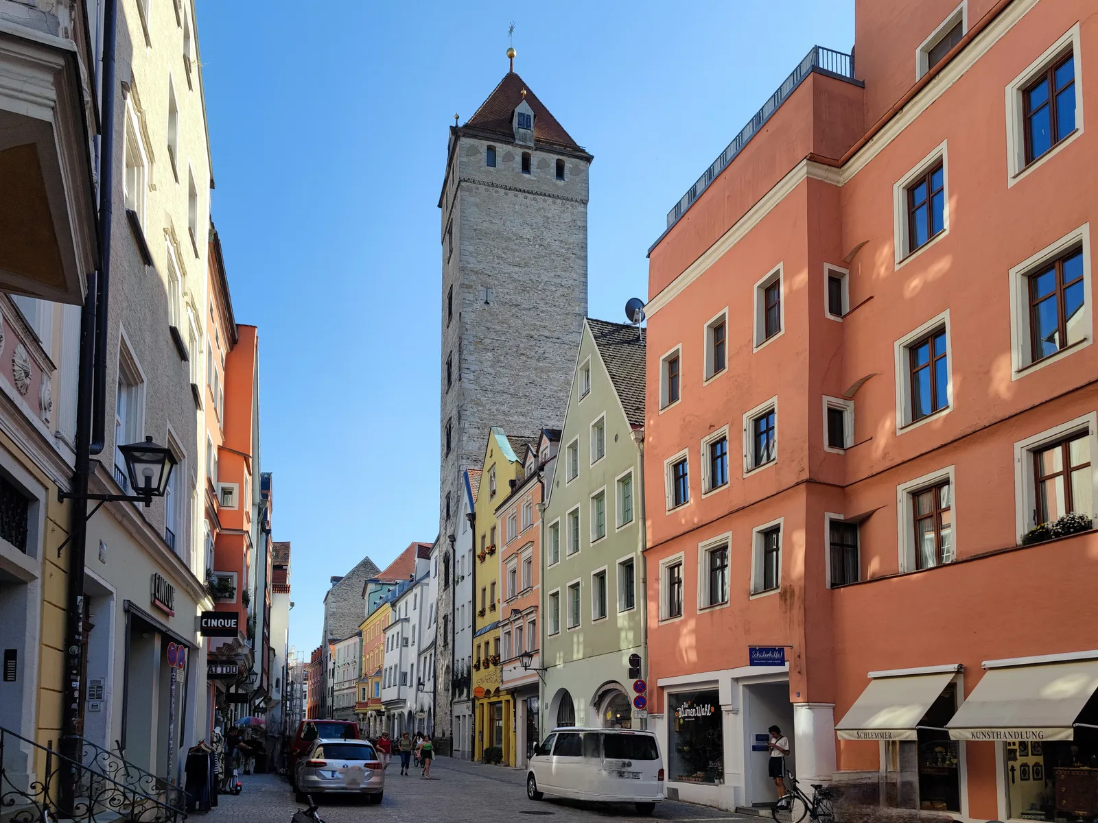 The Goldener Turm tower rising over a narrow old-town street of colourful house fronts in Regensburg.