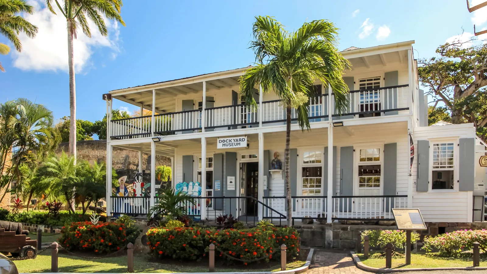 A two-storey white colonial building with wide wooden verandas and palms in Nelson's Dockyard.