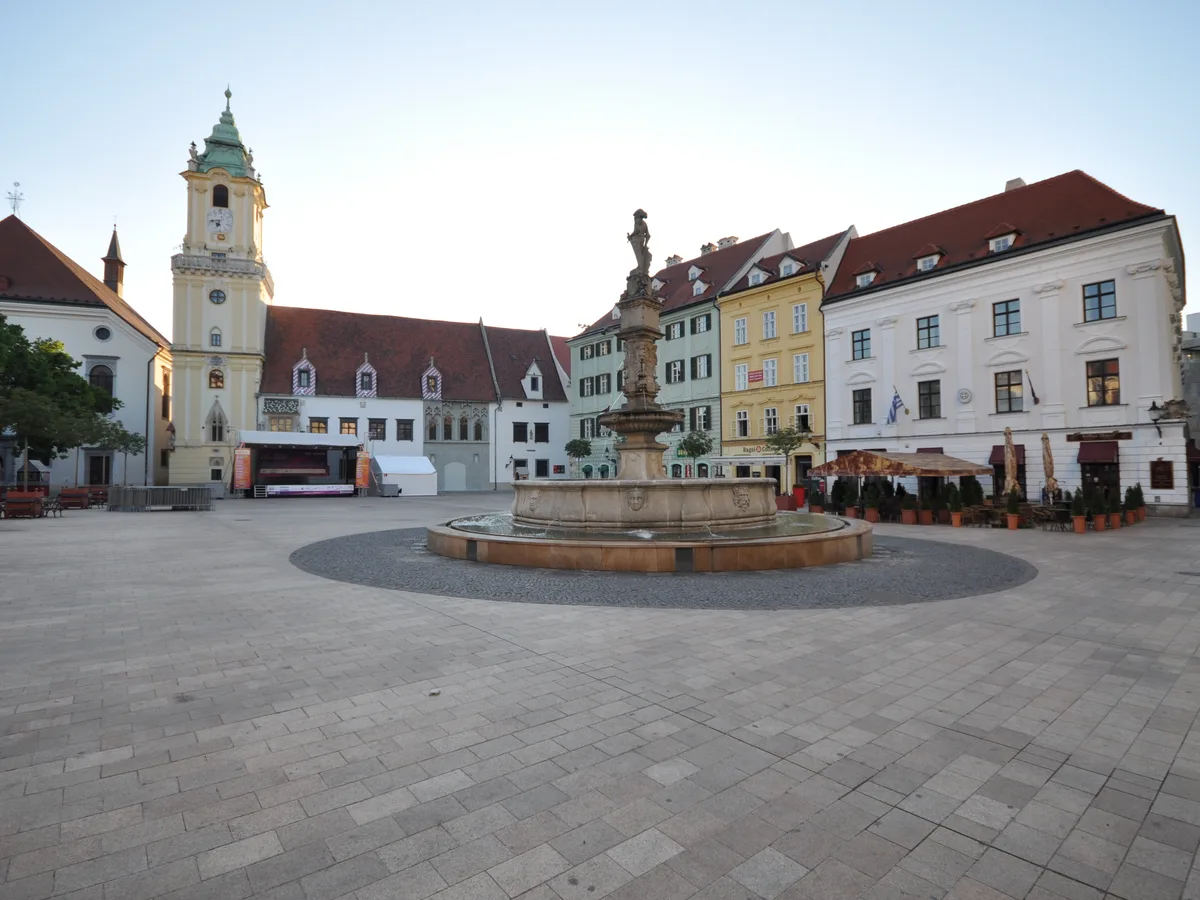 The old town hall tower and the Roland fountain on the empty cobbled main square in early morning light.
