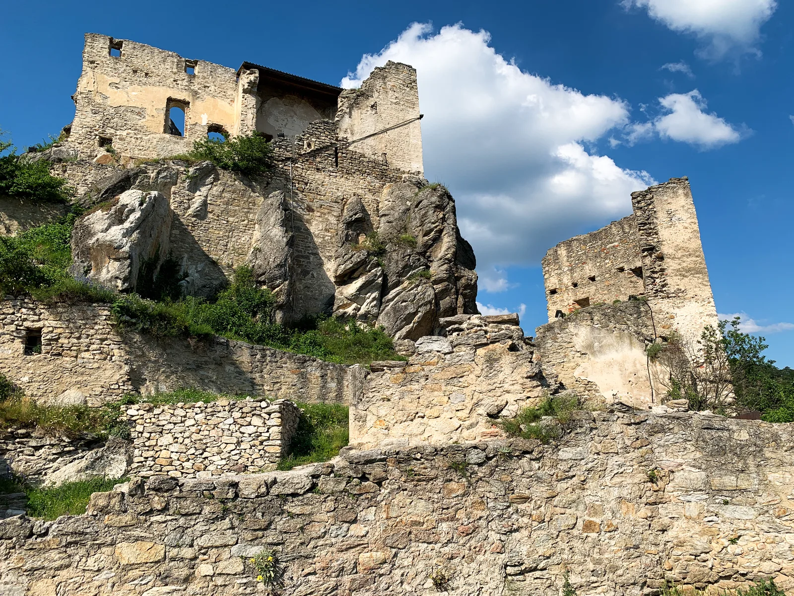 The stone ruins of Dürnstein Castle on a rocky hilltop in bright light.