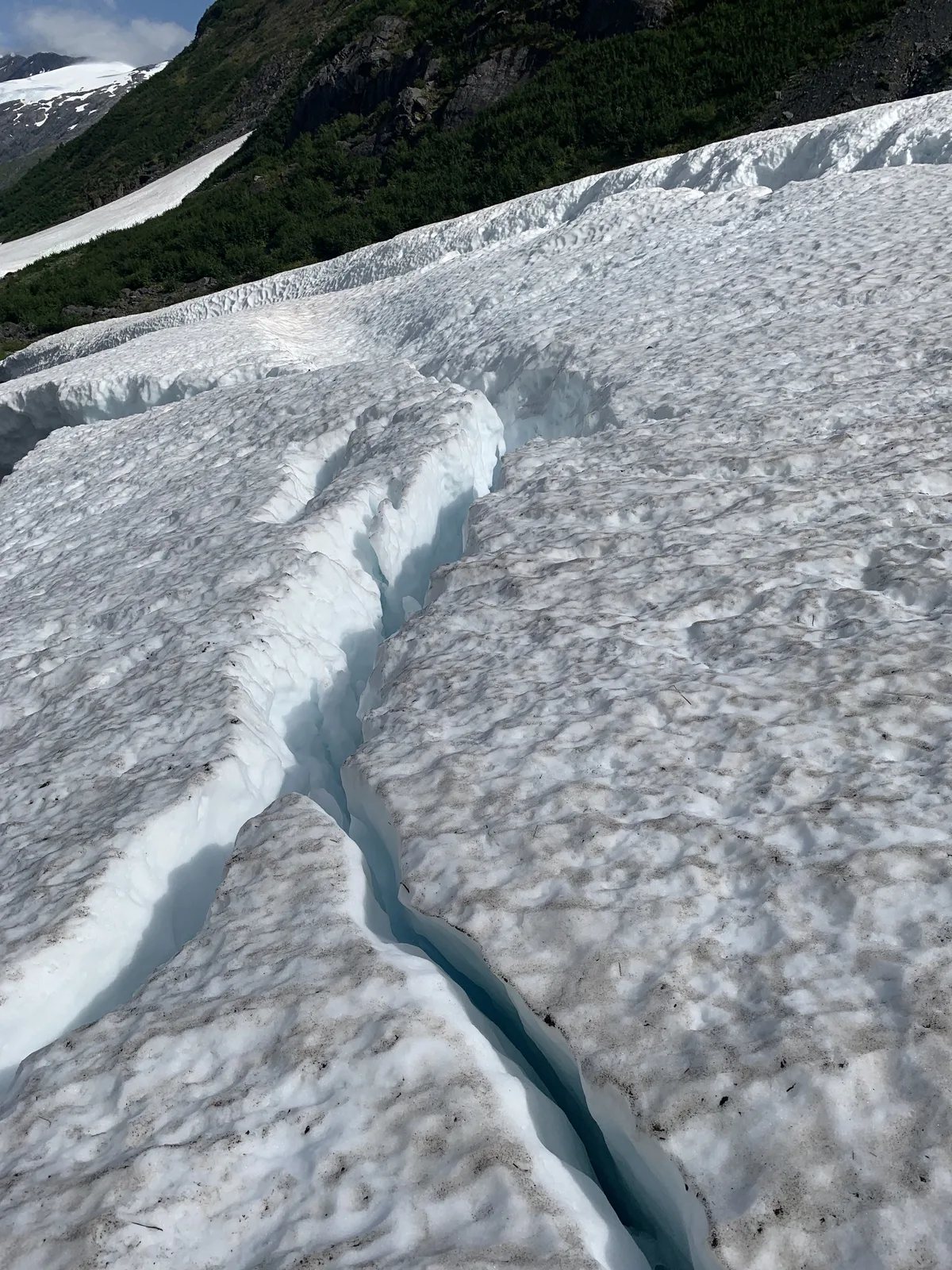 A deep crevasse cutting through an Alaskan glacier's blue ice
