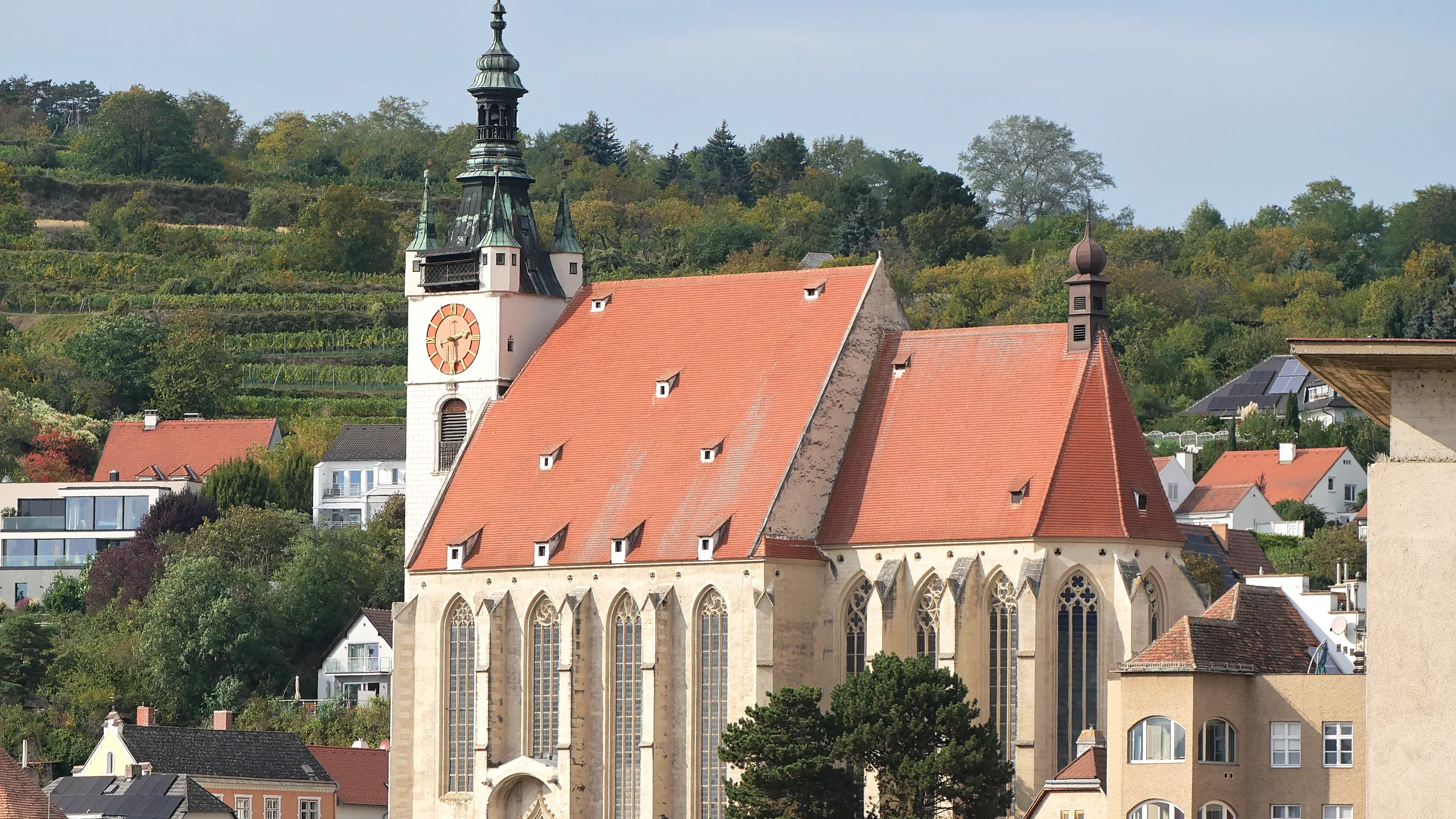 The Piarist church in Krems with its steep red roof and clock tower above terraced vineyard slopes.