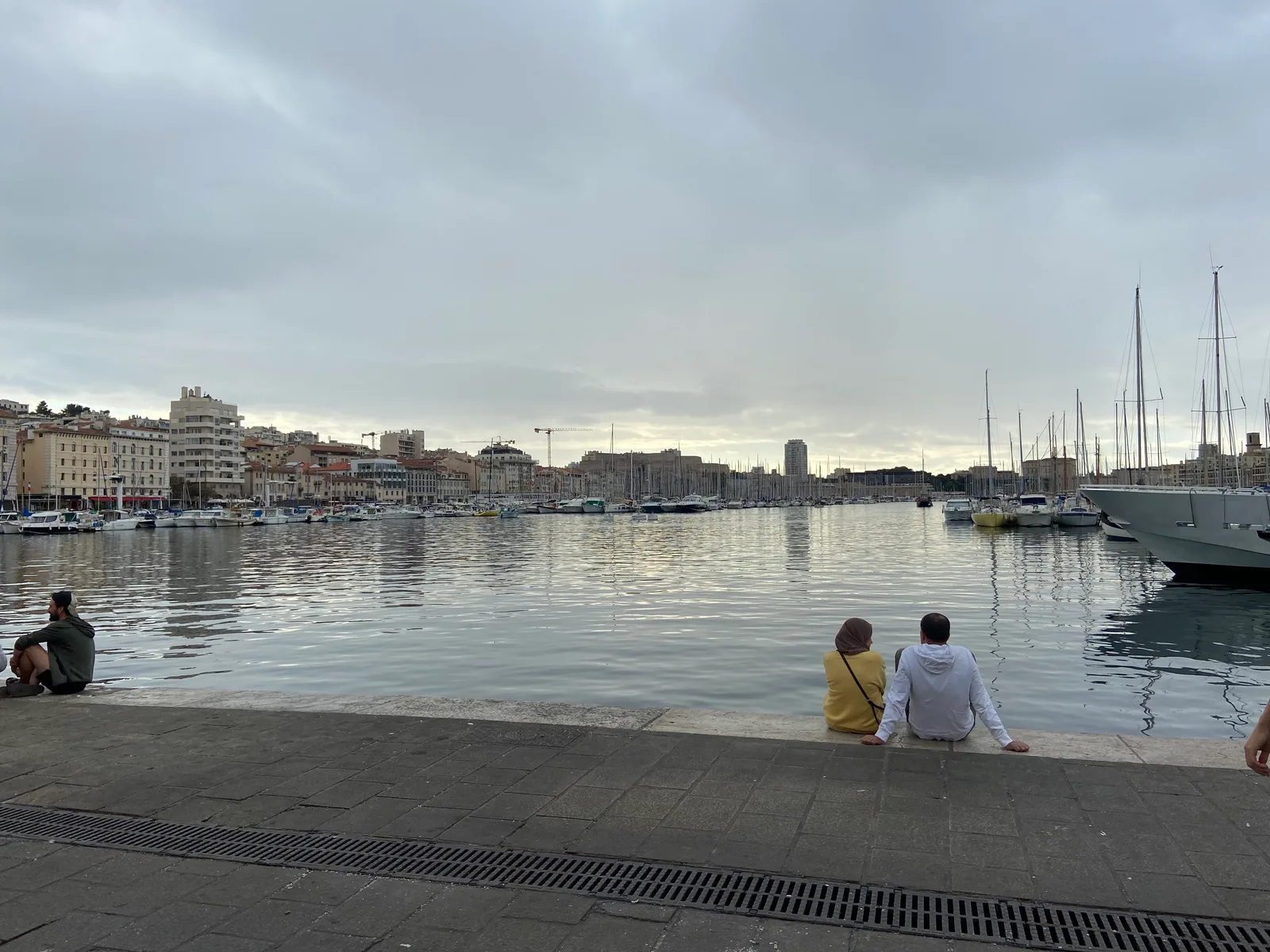 The Vieux-Port of Marseille with moored yachts and masts across calm water under a grey sky.