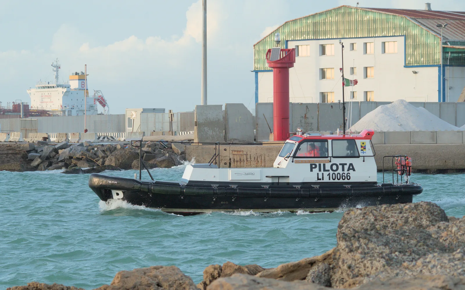 A pilot boat leaving the port of Livorno past a breakwater.
