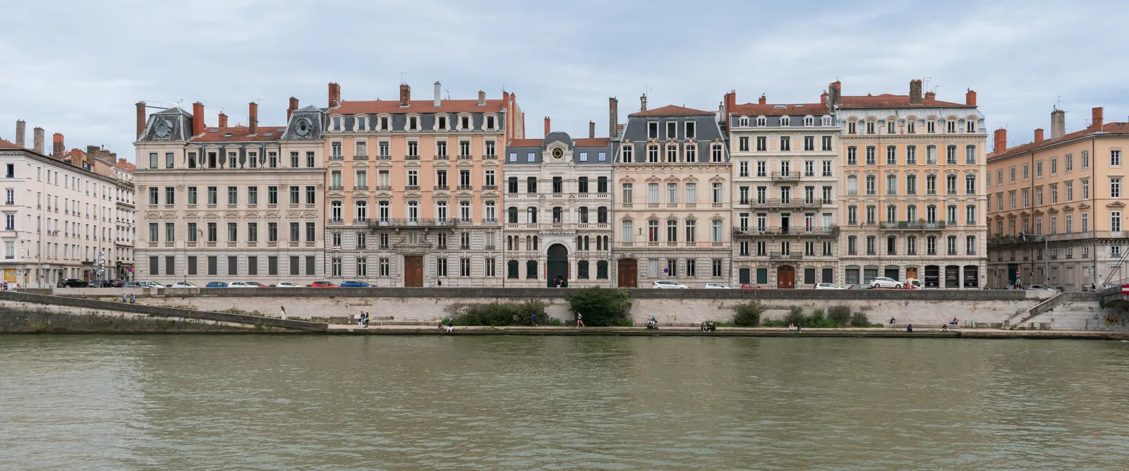 A wide row of tall ornate apartment buildings along the Saône quai at Lyon in even light.