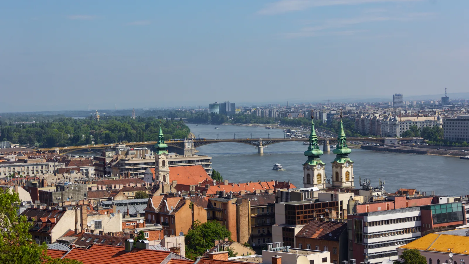 The Danube with Margaret Bridge in the distance and Pest rooftops and church towers in the foreground.