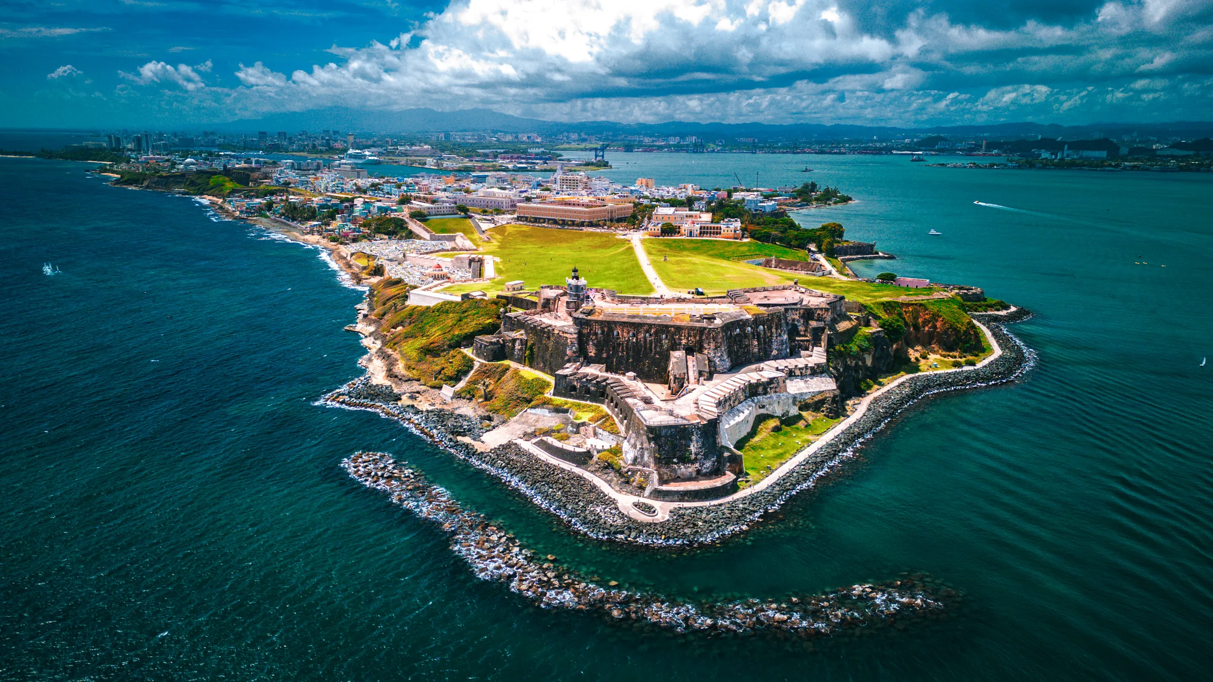 Aerial view of the Castillo San Felipe del Morro fort and its green lawn on the headland at the entrance to San Juan Bay.