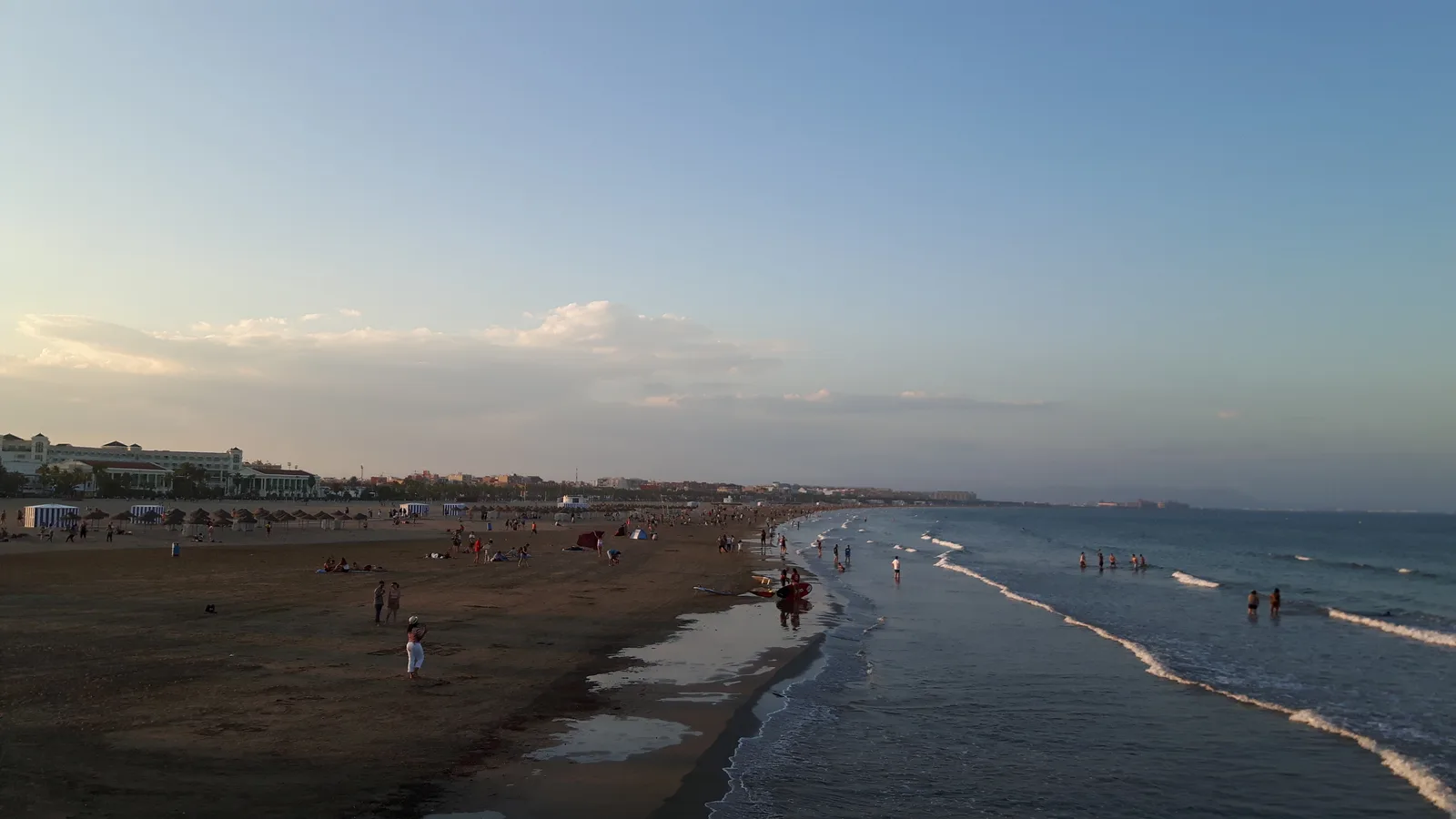 A broad sandy Malvarrosa beach in Valencia at dusk with calm surf.
