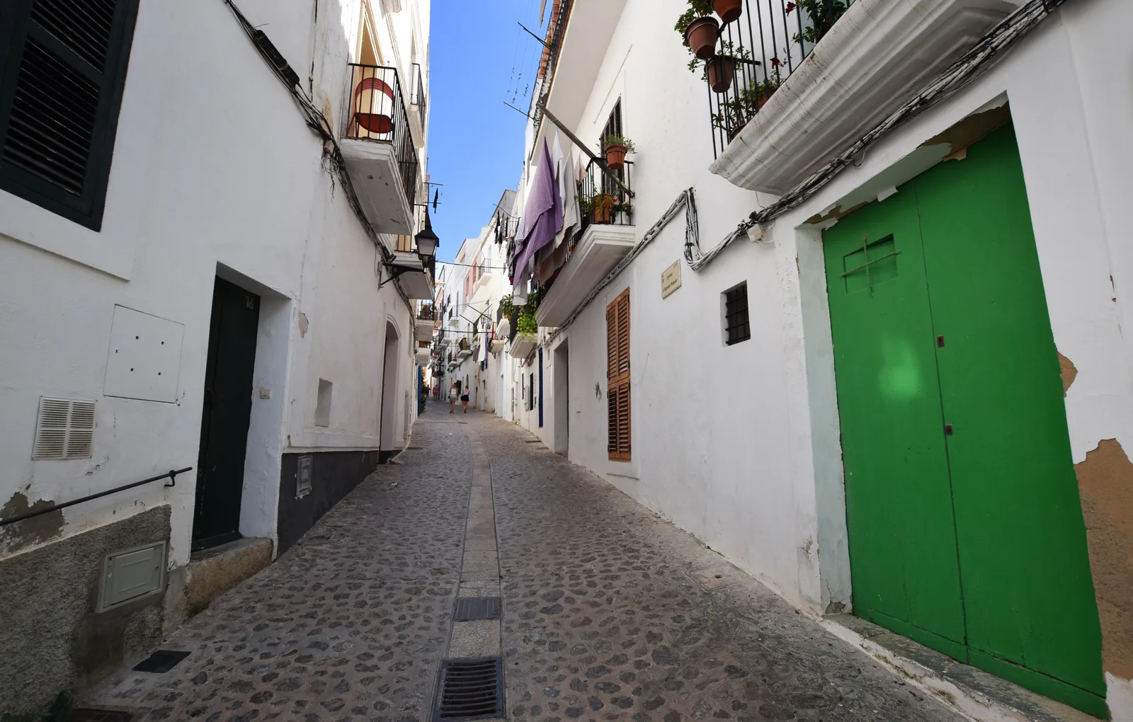 A narrow whitewashed lane in Ibiza old town with a green door and cobbles.