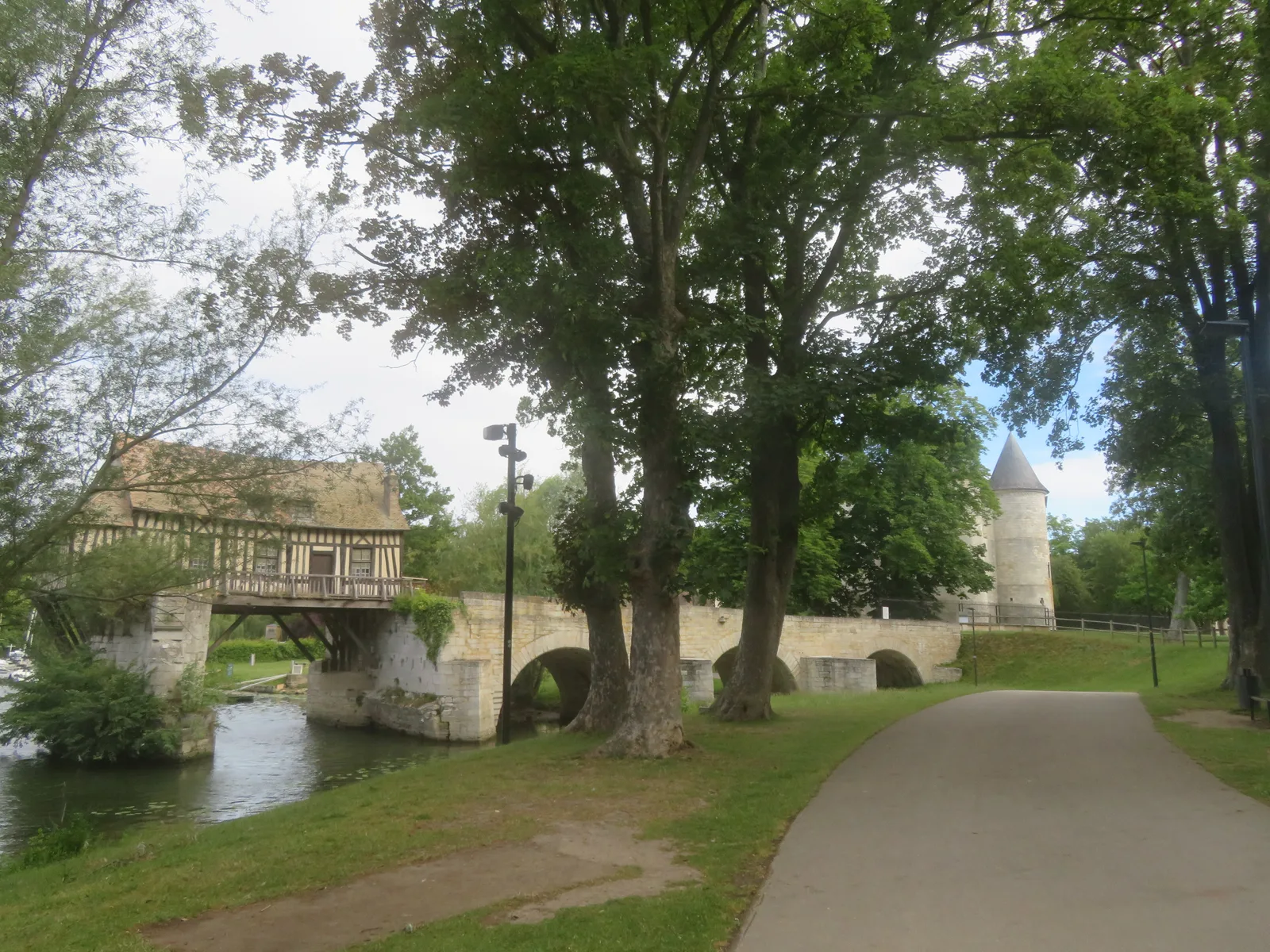 The Vieux Pont and Vieux Moulin at Vernon seen from a tree-shaded greenway with a round tower on the right.