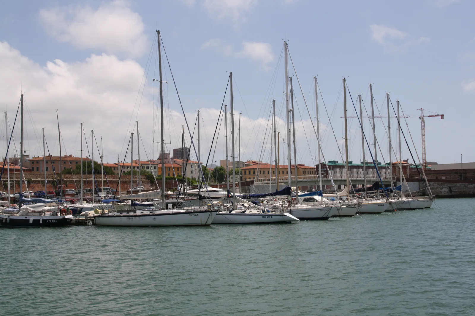 Sailing boats and masts in the Porto Mediceo marina with the town buildings behind.