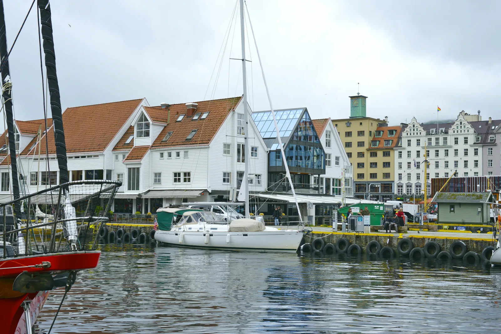 White timber houses and moored sailboats on Vagen harbour in Bergen with a marina in front.