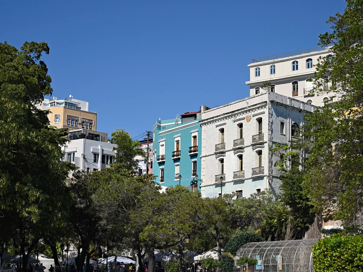 Pastel colonial buildings and mature trees seen from Paseo de la Princesa in Old San Juan.